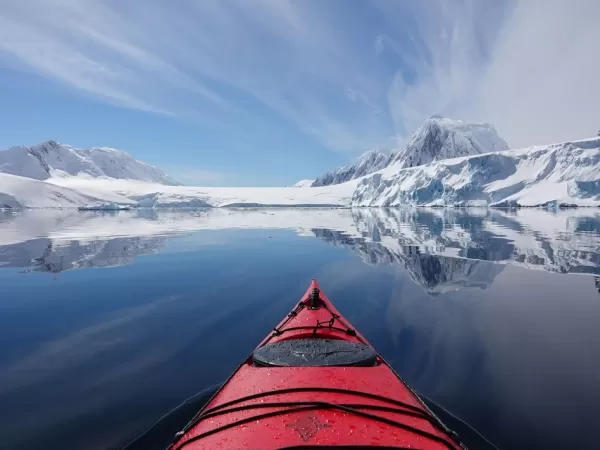 Kayak facing Antarctic mountains across calm water